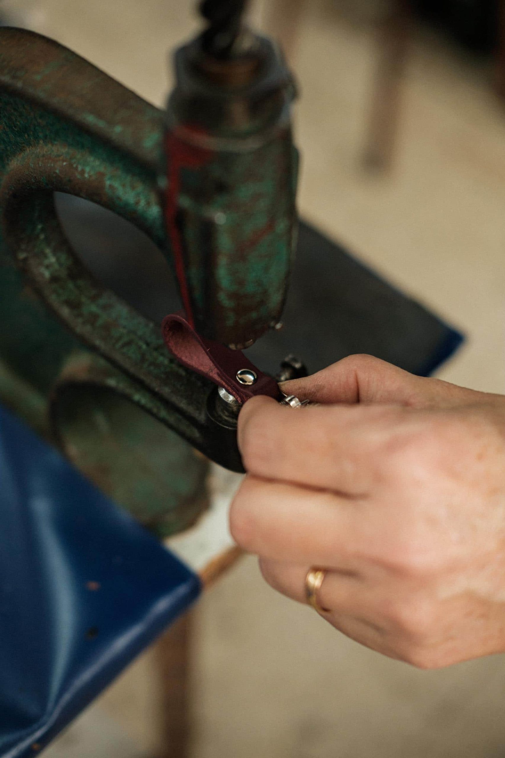 Application of a stud on a small leather loop with the help of a specific tool.