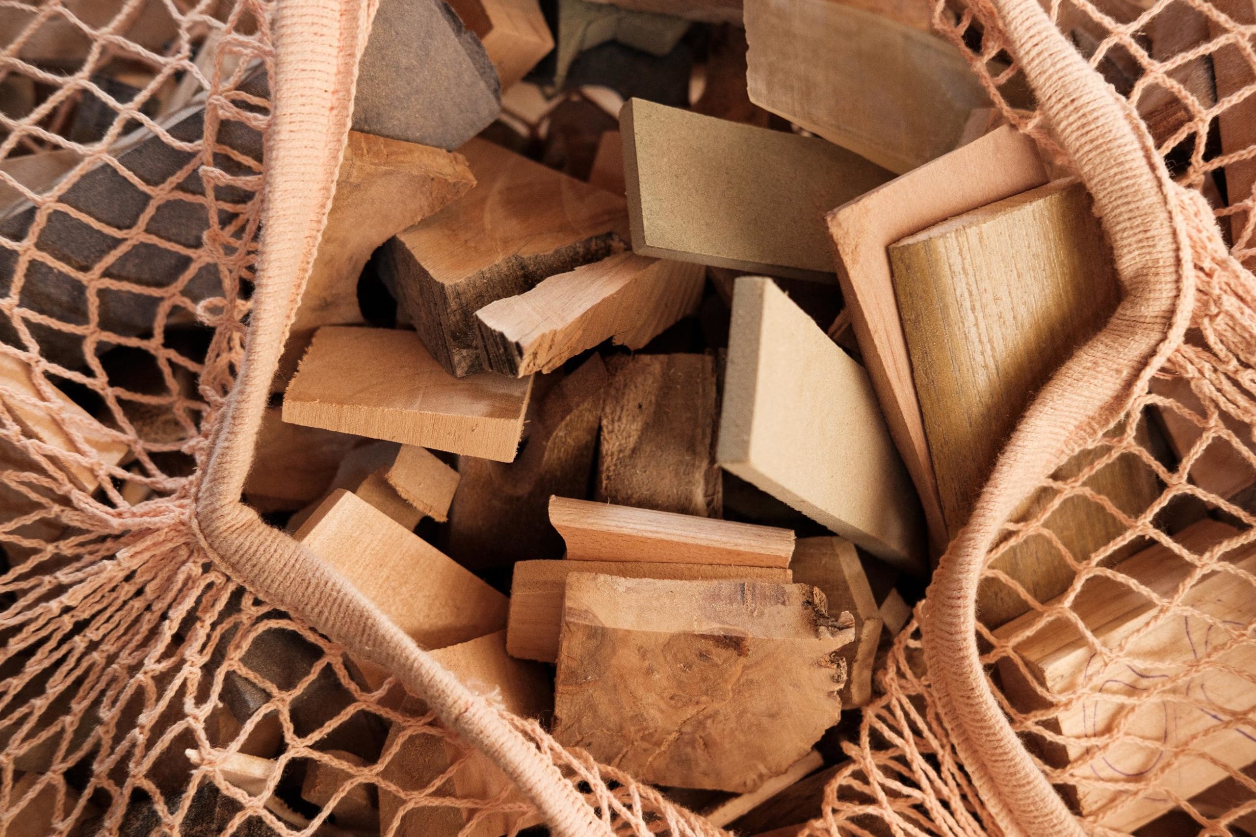 Pedaços de madeira variada dentro de um saco de rede.