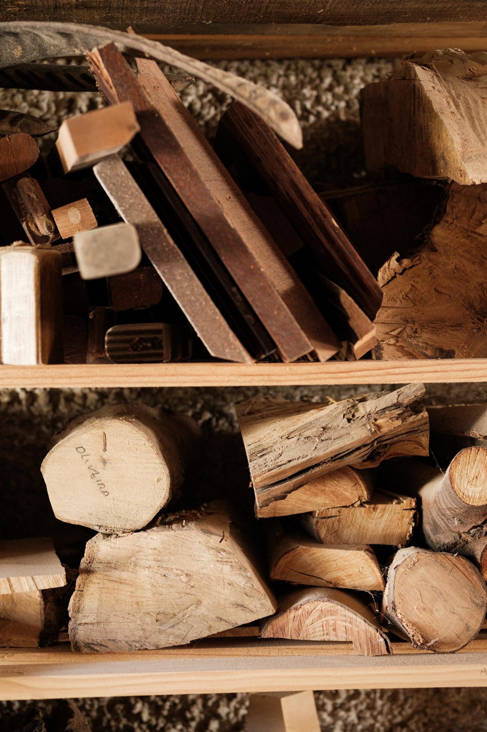 Peças de madeira diversa e de várias formas empilhadas em duas prateleiras.