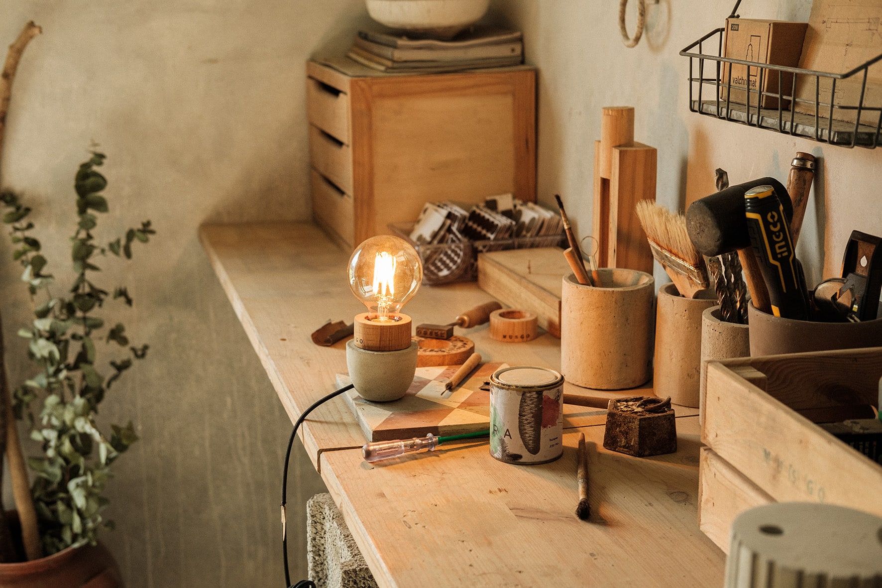 Bancada de atelier de madeira, vários materiais de madeira e candeeiro Musgo finalizado, de luz acessa, ao centro.