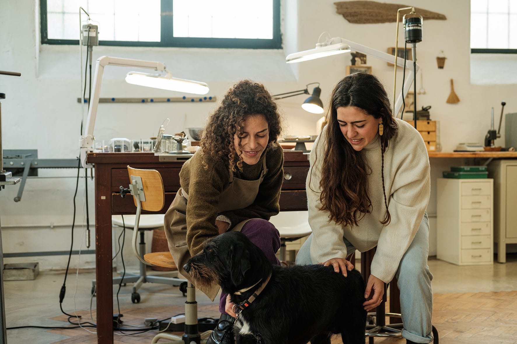 Inês Telles e a sua colega dão festas a um cão no atelier.
