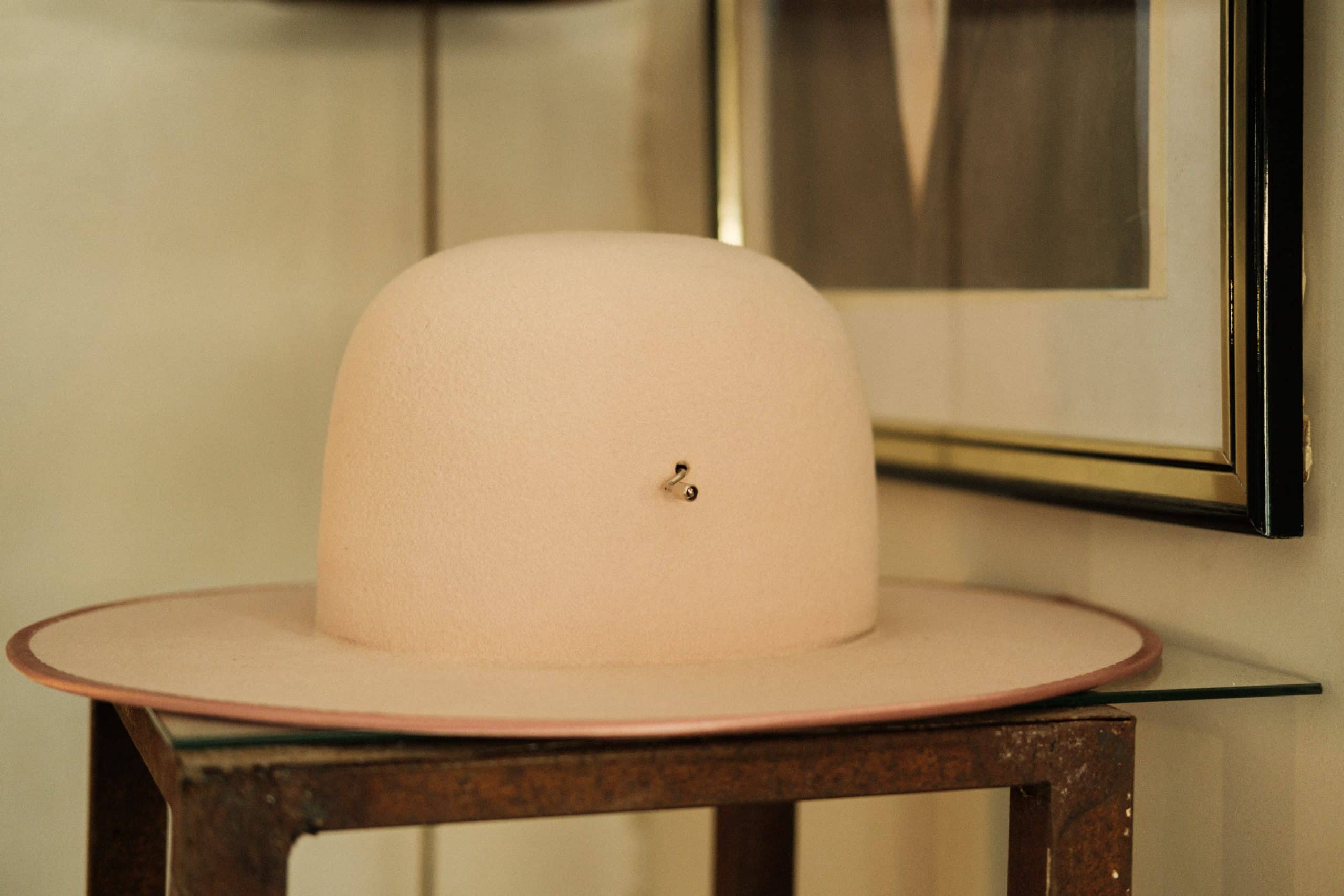 Chapéu rosa suave sobre mesa de madeira.