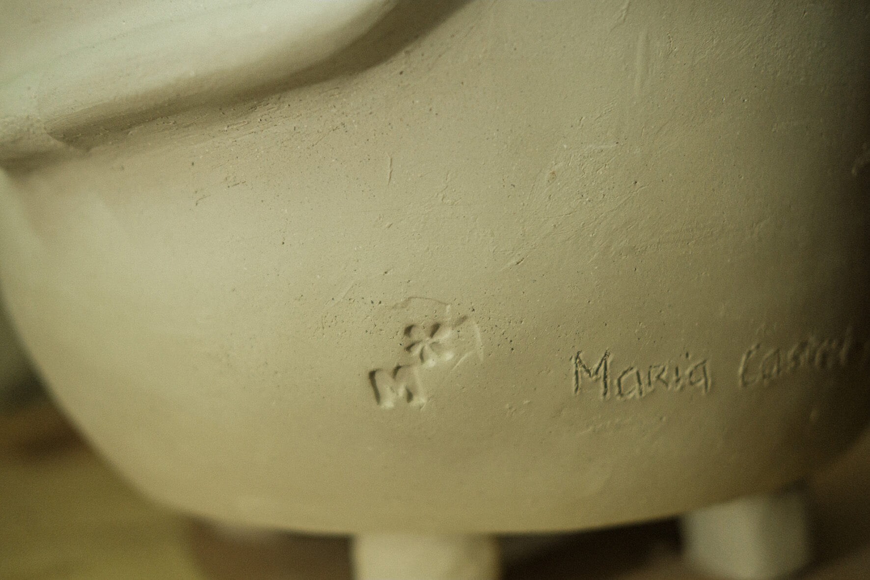 Pormenor de carimbo e nome da ceramista numa peça de cerâmica.
