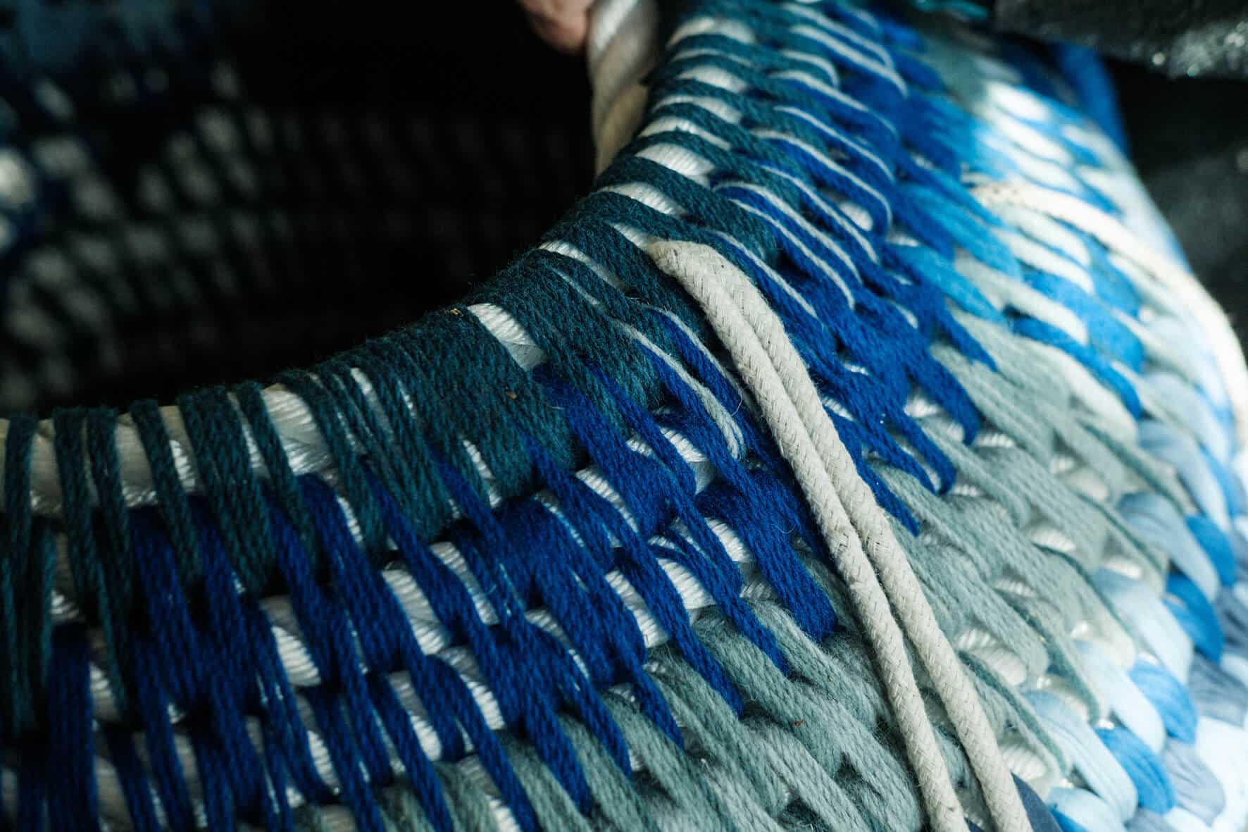Detalhe de peça feita com fios azuis e cordas.