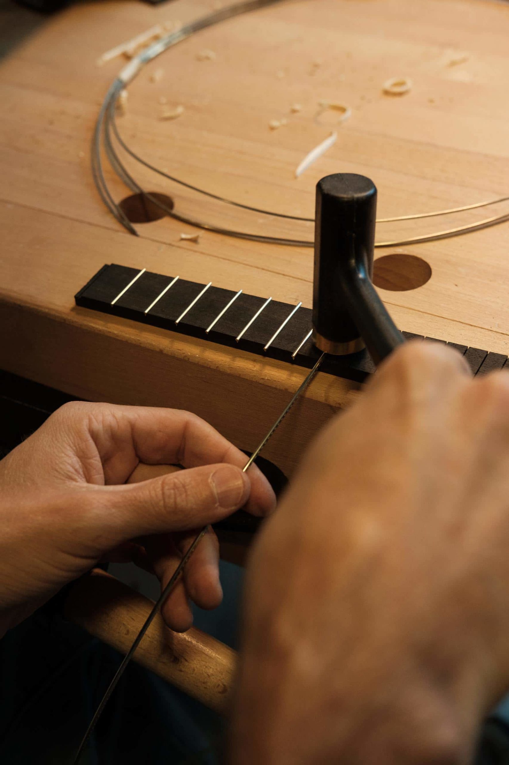 Mãos do artista Leonardo Afonso trabalham no braço da guitarra.