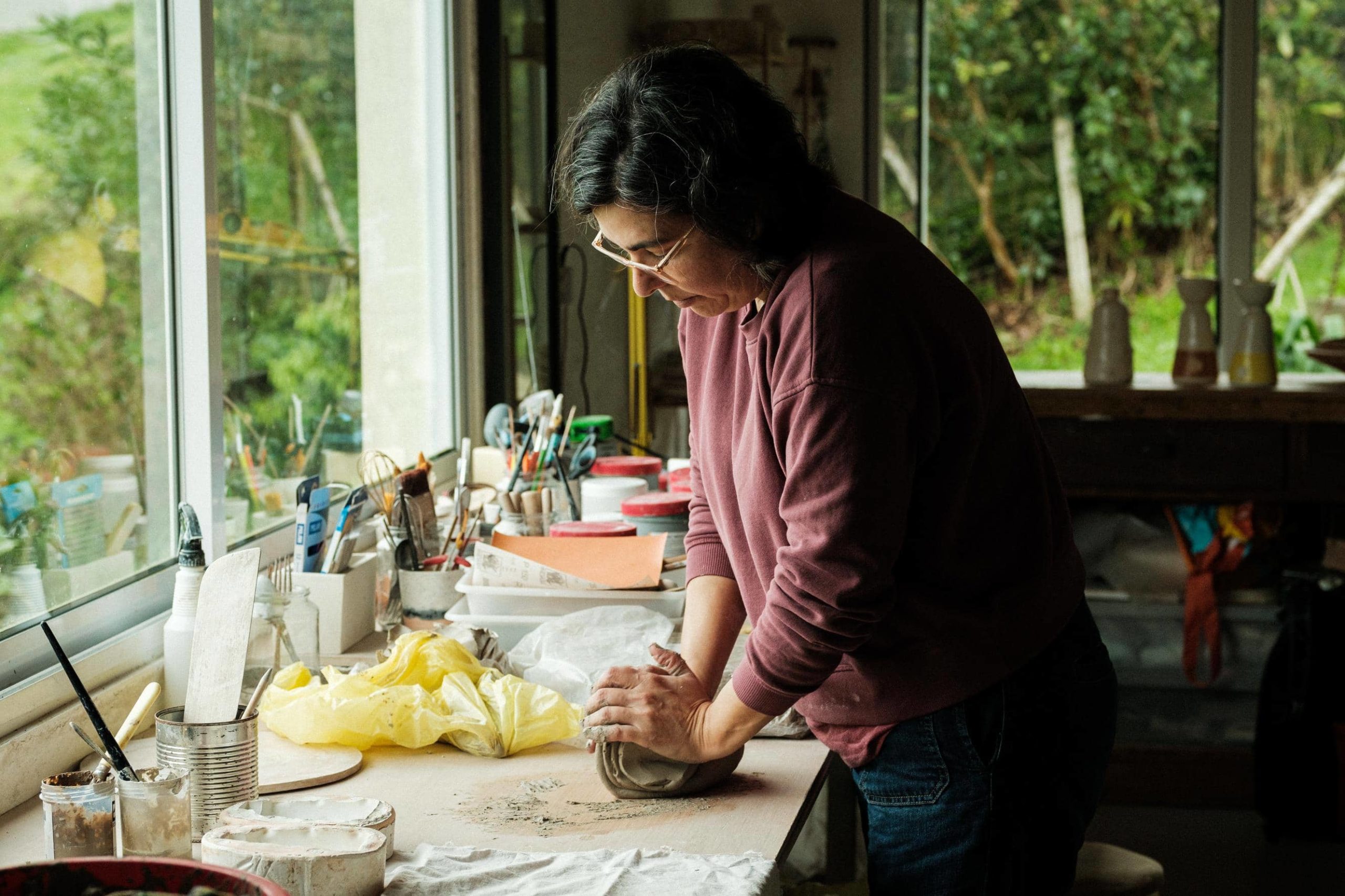 Marina Mendonça amassa barro em cima da banca do seu atelier.
