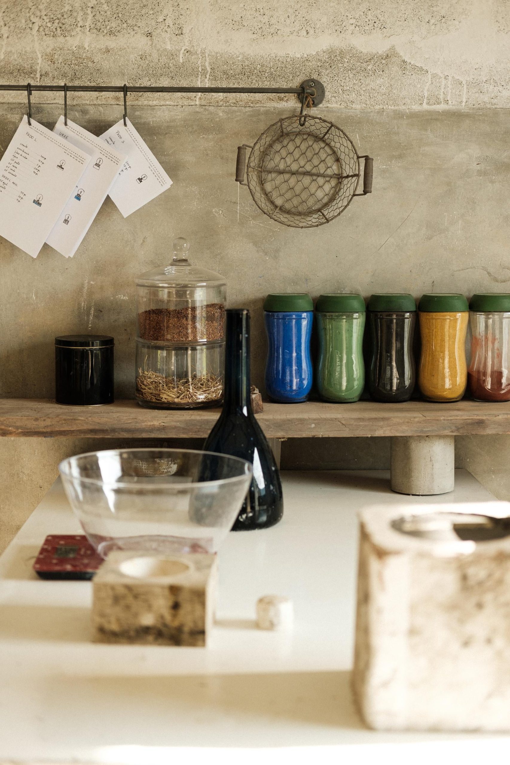 Pigmentos diferentes em frascos, materiais de trabalho, moldes de gesso, organizados em cima de bancada de atelier.