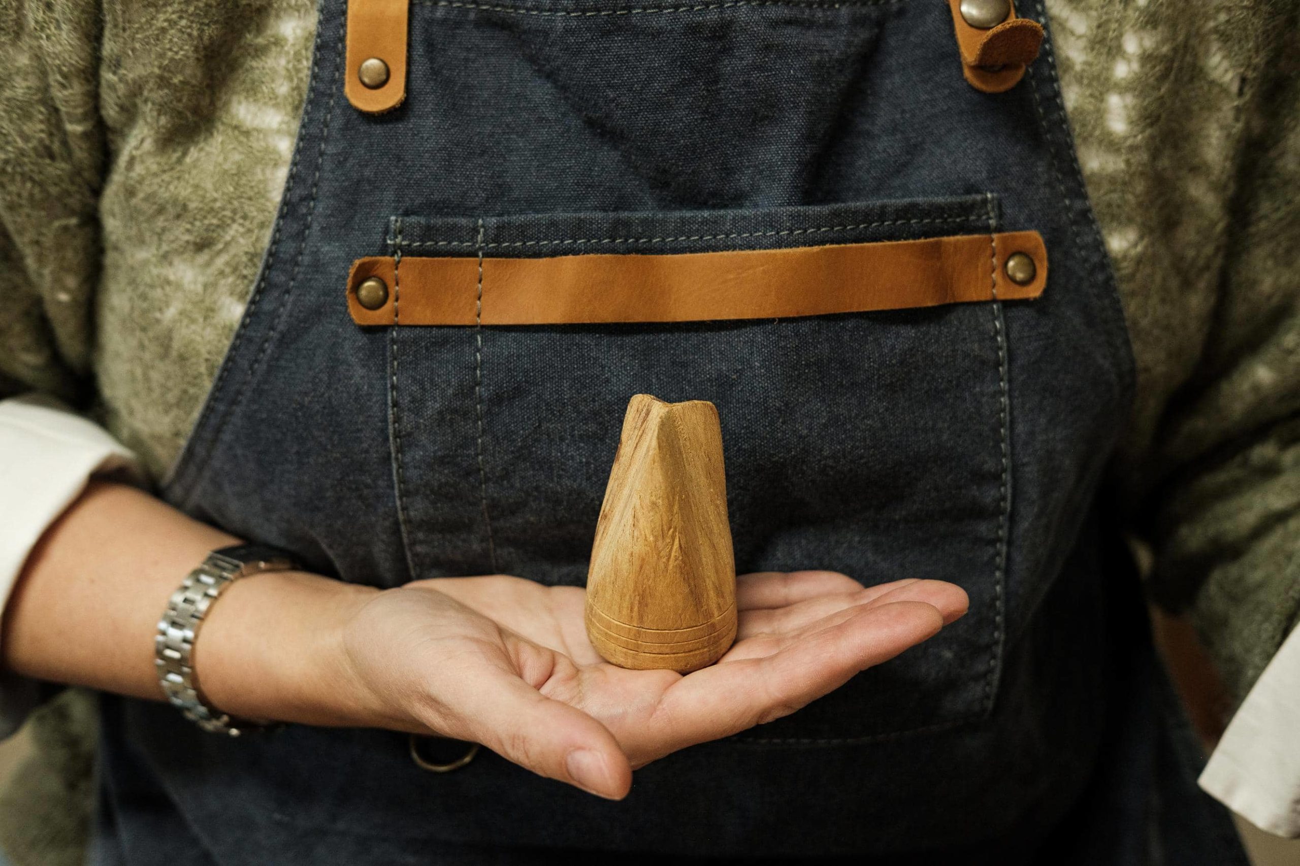 Mão da artesã Catarina a segurar numa ferramenta de madeira.