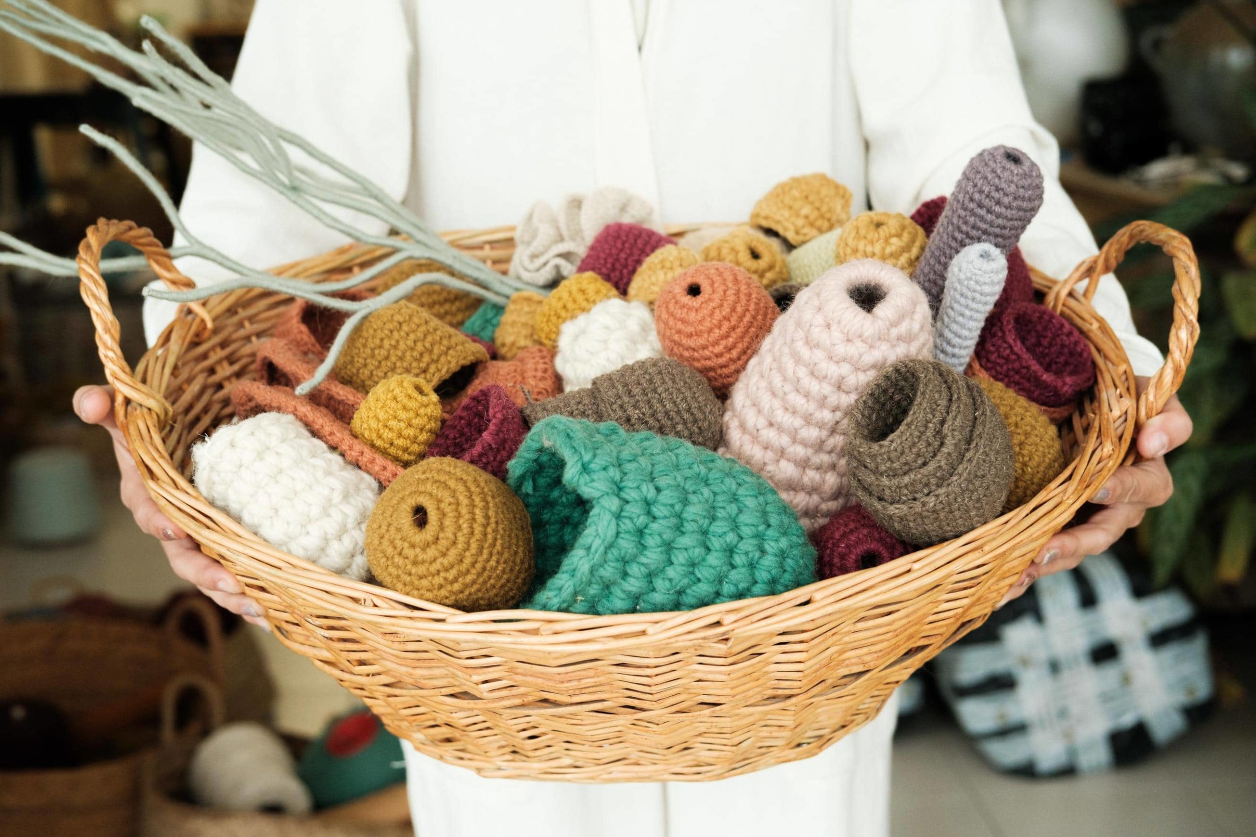 Vanessa segura uma cesta cheia de várias peças coloridas de crochê.