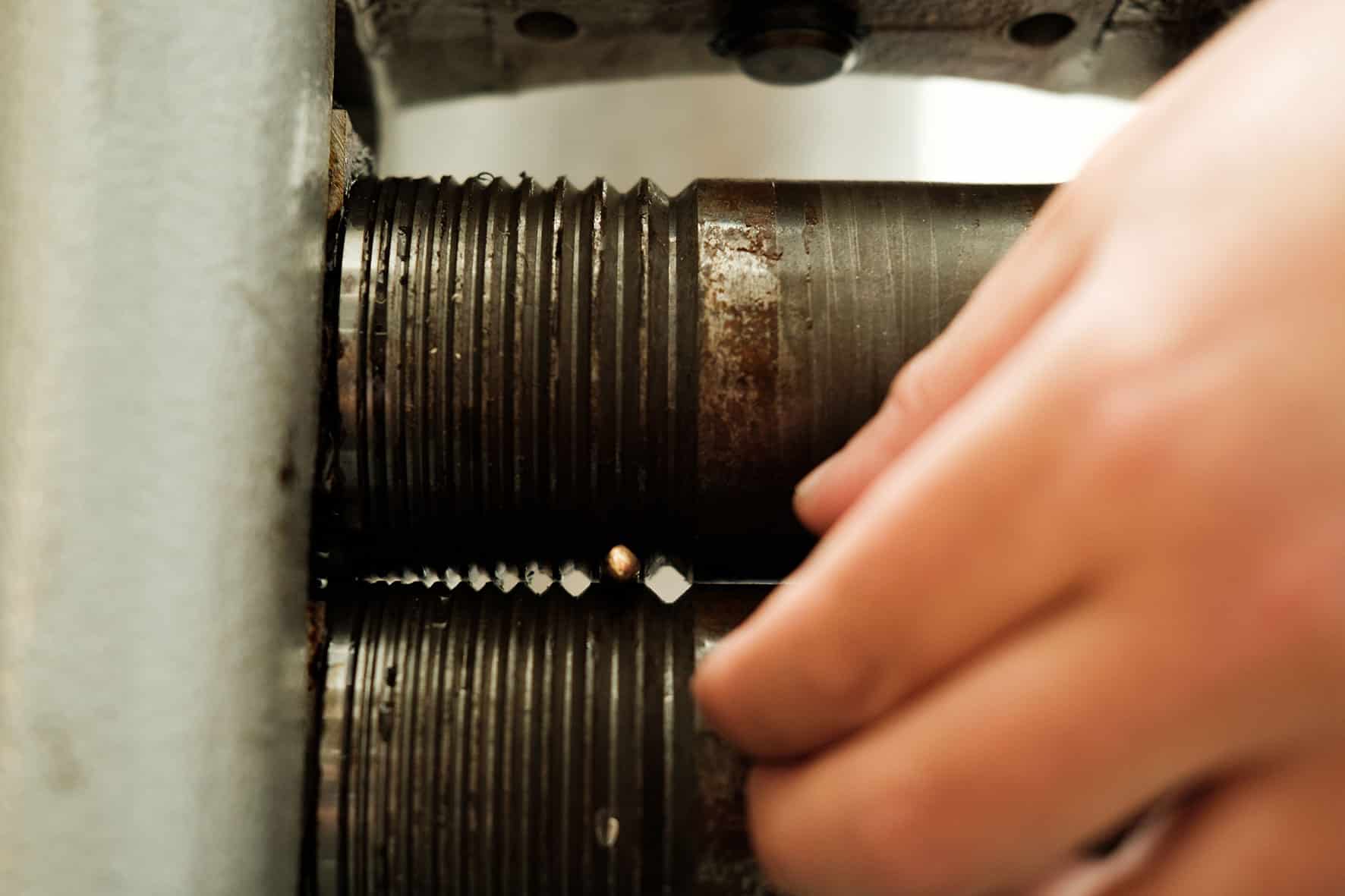 Detail of a gold piece passing through the press to balance its diameter.