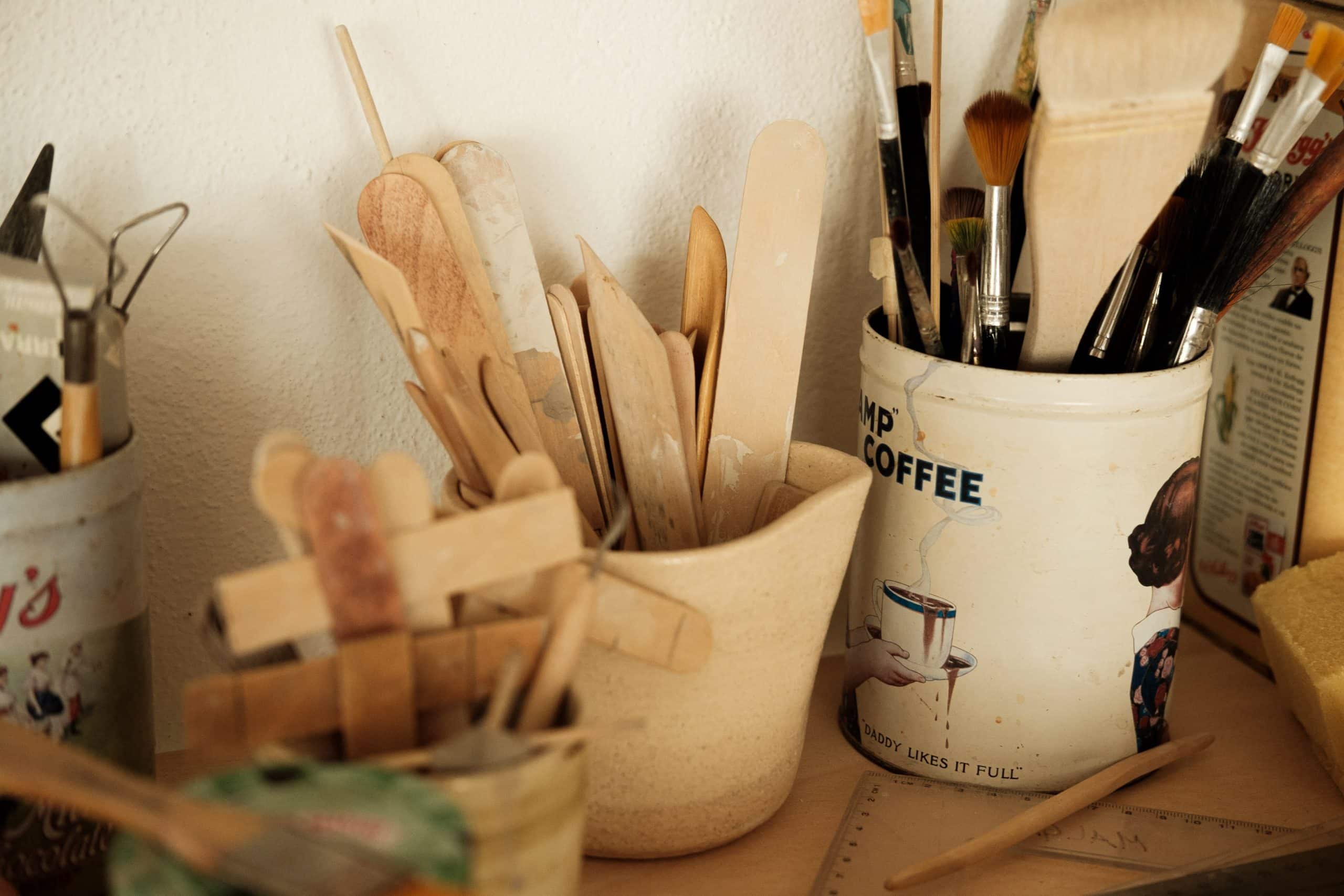 Copos com diversos tipos, formas e cores de lápis e utensílios de madeira.