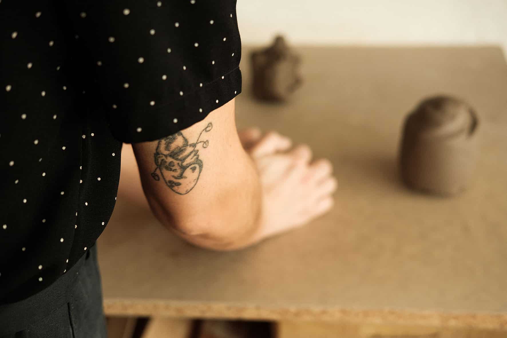 Detalhe da tatuagem no braço da ceramista, enquanto trabalha o barro.