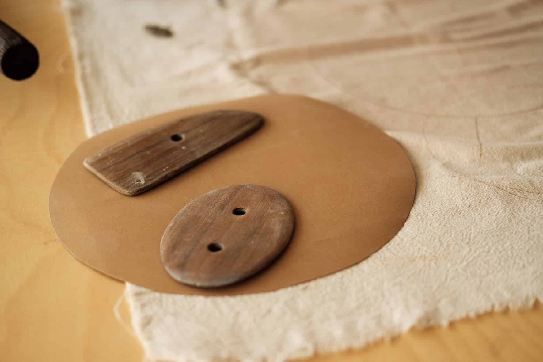 Detalhe aproximado de dois raspadores de madeira sobre tecido de pano cru.